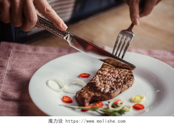 一个人正在使用刀叉吃牛排西餐牛排